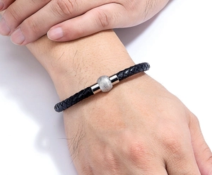 Dettaglio del bracciale in pelle intrecciata con sfera d'argento opaca e chiusura magnetica