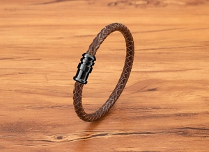 Close-up of brown braided leather bracelet with black magnetic clasp on wood