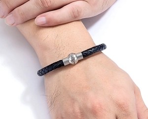 Dettaglio del bracciale in pelle nera intrecciata con fibbia magnetica in acciaio e texture