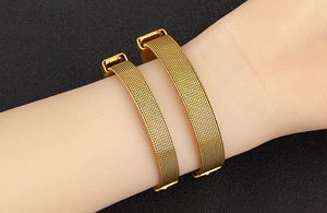 Detailed view of two gold Milanese mesh bracelets with adjustable square buckles