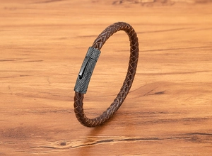 Detailopname van bruine gevlochten leren armband met zwarte gekartelde metalen sluiting