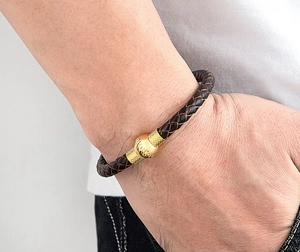 Vista dettagliata del bracciale in pelle intrecciata da uomo con dettagli dorati
