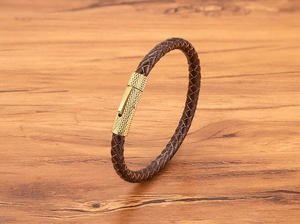 Detail van donkerbruine gevlochten leren armband met een goudkleurige metalen sluiting