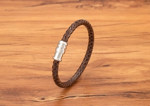 Detail of a brown braided leather bracelet with a cylindrical silver magnetic clasp