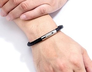 Detail of black braided leather bracelet for men with silver stainless steel clasp