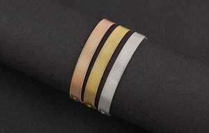 Detail of Milanese mesh bracelets in rose gold, gold, and silver on a black display
