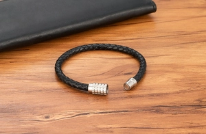 Detail of three-strand braided leather bracelet with stainless steel magnetic clasp on wood