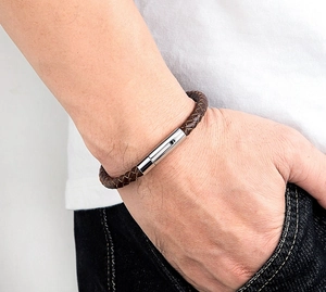 Detail eines dunkelbraunen Lederarmbands mit poliertem Edelstahlverschluss am Handgelenk