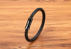 Detailed close-up of a black braided leather bracelet with a matte magnetic clasp on wood