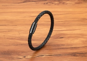Detail of three-strand braided black leather cord and textured steel magnetic clasp