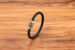 Dettaglio bracciale in pelle nera intrecciata con chiusura magnetica oro a righe