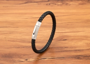 Detailed close-up of a black braided leather bracelet with a silver brushed metal clasp
