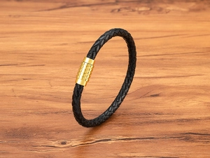 Detail of golden magnetic clasp with grid texture on black braided leather bracelet