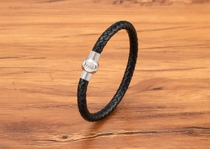 Dettaglio macro del bracciale in pelle nera intrecciata da uomo con chiusura magnetica