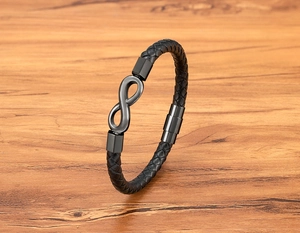 Close-up of black braided leather bracelet featuring a gray infinity symbol metal charm