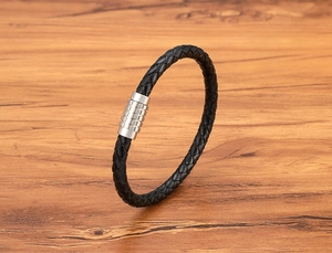 Detail of black braided leather men's bracelet with cylindrical stainless steel magnetic clasp