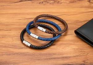 Dettaglio di bracciali in pelle intrecciata neri, blu e marroni con chiusure in metallo