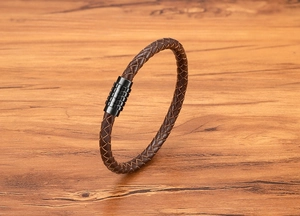 Macro detail of brown braided leather bracelet with black textured metal magnetic clasp