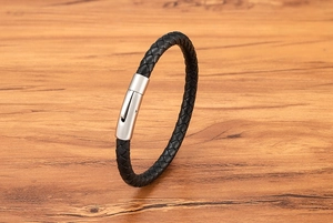 Detail of black braided leather bracelet with a polished silver press-lock clasp
