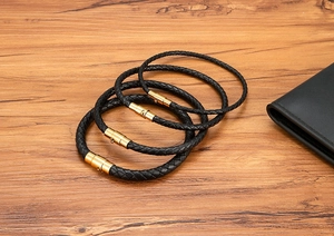 Detailed macro of four braided black leather bracelets with golden magnetic metal clasps