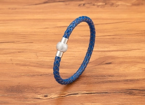 Dettaglio di un bracciale in pelle intrecciata blu con chiusura magnetica in acciaio
