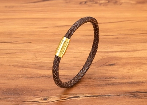 Close-up of brown braided leather strap with textured gold magnetic metal clasp