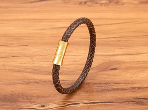 Detail of braided dark brown leather bracelet with a polished gold magnetic metal clasp