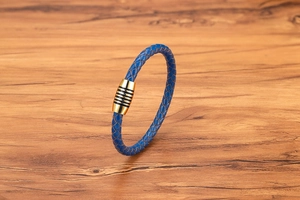 Dettaglio del bracciale in pelle intrecciata blu con chiusura magnetica dorata e neri