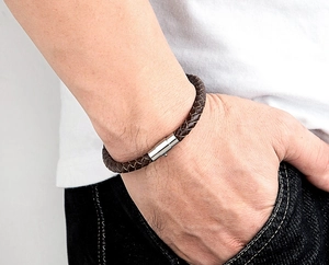 Dettaglio del bracciale in pelle intrecciata marrone da uomo con fibbia magnetica in argento