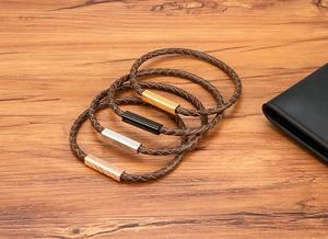 Close-up of four brown braided leather bracelets with gold, silver, black, and rose gold magnetic clasps