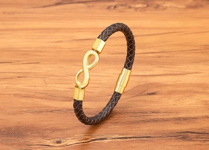 Detail of infinity charm on brown braided leather bracelet with golden magnetic clasp
