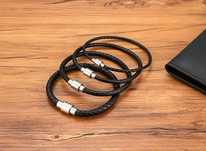 Detail of four black braided leather bracelets with polished silver magnetic steel clasps