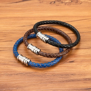 Three-color braided leather bracelets with silver magnetic clasps on wood background
