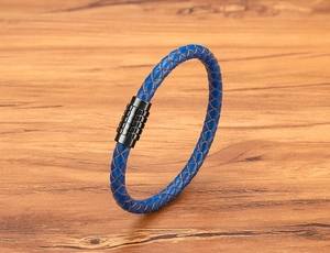 Macro shot of blue braided leather texture and black textured magnetic clasp on wood