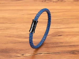 Macro detail of blue braided leather cord with matte black magnetic clasp on wood