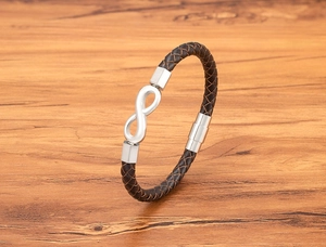 Detail of 6mm brown braided leather bracelet with silver infinity symbol on wood