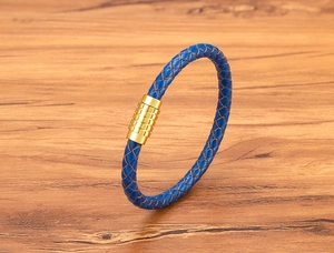 Detailed close-up of woven blue leather strap with gold magnetic clasp on wood