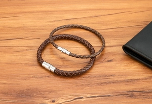 Dettaglio di braccialetti in pelle intrecciata marrone scuro con chiusura in acciaio inox