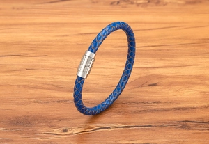 Detailed close-up of a blue woven leather bracelet with a textured magnetic steel clasp