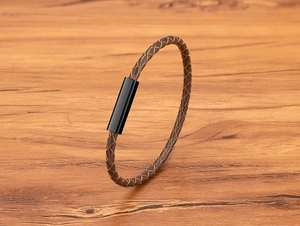 Close-up of brown braided leather bracelet with a sleek black magnetic clasp on wood