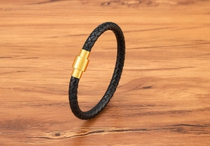 Close-up of black braided leather bracelet featuring a gold magnetic stainless steel clasp