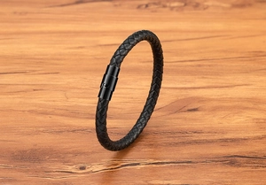 Detail of black braided leather men's bracelet with a matte black magnetic clasp
