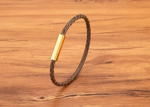 Detailed close-up of brown braided leather bracelet with a polished gold magnetic clasp