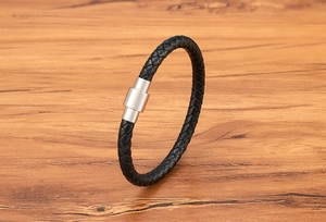 Detail of black braided leather bracelet with a cylindrical stainless steel magnetic clasp