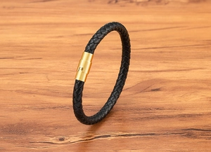 Detail of black braided leather bracelet featuring a polished gold stainless steel magnetic clasp