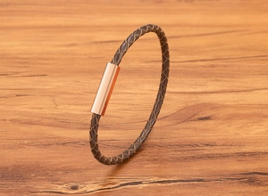 Detail of brown braided leather bracelet with rose gold magnetic stainless steel clasp