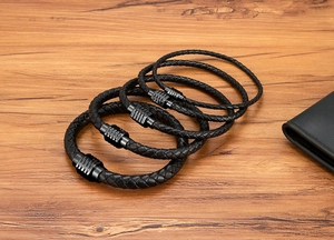 Dettaglio di quattro bracciali in pelle intrecciata con fibbie magnetiche nere opache