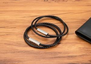 Macro detail of black braided leather men bracelet with polished silver magnetic clasp