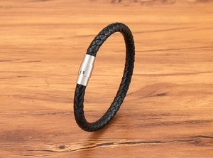 Macro detail of black braided leather bracelet with silver magnetic stainless steel clasp