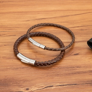 Braune geflochtene Lederarmbänder mit Edelstahlverschluss auf einem Holztisch